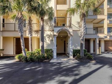 Welcoming condo building entrance featuring a decorative archway, lush landscaping, and secure access at 830 The Esplanade N # 201, Venice, FL 34285
