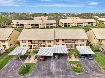 Aerial view of a two-story condo community with carports and well-maintained landscaping at 410 Mission E Trl # H, Venice, FL 34285