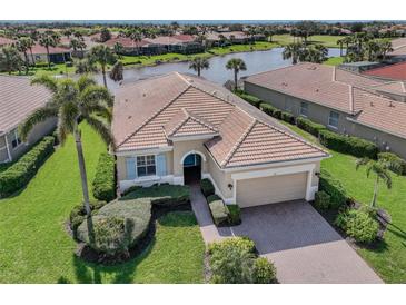 Inviting single-story home with a clay tile roof, lush landscaping, and a tranquil lake view at 129 Cipriani Way, North Venice, FL 34275