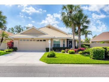 Inviting single-story home with a well-maintained lawn and mature palm trees at 1330 Berkshire Ct, Venice, FL 34292