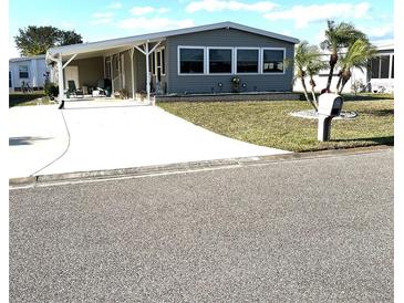 Charming gray home with a carport, manicured lawn, and lush palm trees at 199 Palm Harbor Dr, North Port, FL 34287