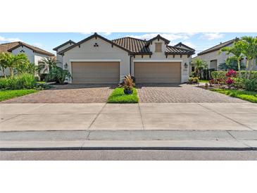 Inviting two-story home featuring a brick driveway, tan exterior, and two-car garage at 27440 Janzen Ct, Englewood, FL 34223