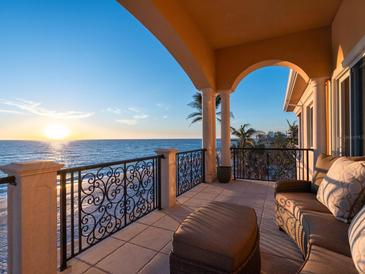 Inviting balcony view with ocean backdrop, stylish furniture, and ornate iron railing offering relaxation and scenic beauty at 2821 Casey Key Rd, Nokomis, FL 34275