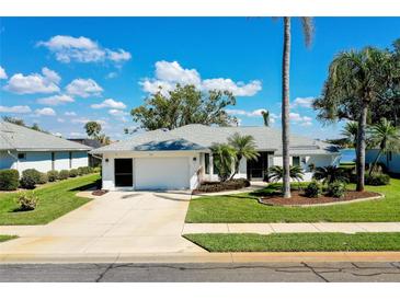 Charming single-story home with a well-manicured lawn, mature trees, and a two-car garage at 562 Silk Oak Dr, Venice, FL 34293