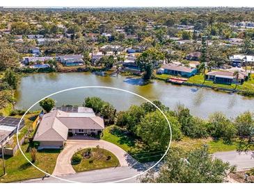 Waterfront home features mature landscaping, circle driveway, and screened-in pool at 6146 Rockefeller Ave, Sarasota, FL 34231