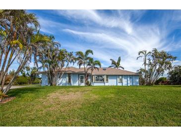 Single story home with light blue paint, palm trees, green grass, blue skies, and a grassy lawn at 8170 Casa De Meadows Dr, Englewood, FL 34224