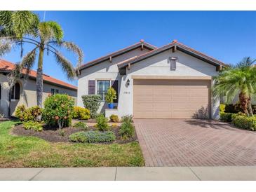 Charming single-story home featuring a well-manicured lawn, brick driveway, and a two-car garage at 10412 Crooked Creek Dr, Venice, FL 34293