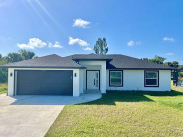 Charming single-story home featuring a modern design, well-kept lawn and two-car garage at 12390 Talavera St, North Port, FL 34287