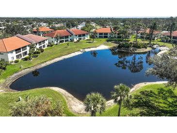Aerial view of the community featuring a tranquil pond, lush landscaping, and well-maintained grounds and buildings at 503 Pine Hollow Cir # 503, Englewood, FL 34223