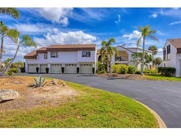 Waterfront condo building featuring a large, lush green area with palm trees and meticulously maintained landscaping at 820 Capri Isles Blvd # 202, Venice, FL 34292