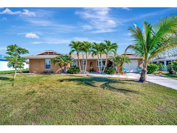 Charming single-story home with a well-manicured lawn, palm trees, and a welcoming facade under a sunny sky at 13534 Alberta Ave, Port Charlotte, FL 33981