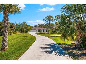 Beautiful home on a large lot, featuring lush landscaping and a long driveway, surrounded by mature trees and blue skies at 1785 Bayshore Dr, Englewood, FL 34223