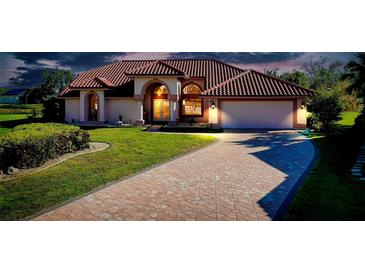Charming single-story home with tile roof, arched entry, brick driveway, and lush lawn at 1886 Killdeer Ct, Venice, FL 34293