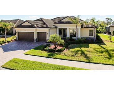 Stunning home featuring a tile roof, two-car garage, manicured lawn, and lush landscaping at 20794 Valprato Ct, Venice, FL 34293