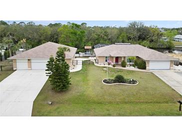 Spacious home with manicured lawn, two garages, and a fenced backyard featuring a sparkling in-ground pool at 31 Ramblewood St, Port Charlotte, FL 33953