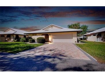 Charming home exterior with lush landscaping, a brick driveway and white tile roof at 49 Sandstone Cir, Venice, FL 34293