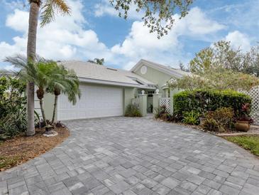 Charming single-Gathering home showcasing a brick paved driveway, lush landscaping, and attached two-car garage at 503 Clubside Cir # 47, Venice, FL 34293
