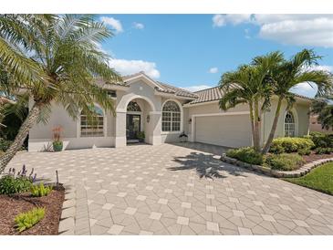 Charming single-story home featuring tropical landscaping, a paver driveway, and a two-car garage at 614 Pond Willow Ln, Venice, FL 34292