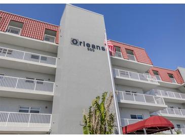 Exterior of condo building with balconies, red roof, and manicured greenery in a beautiful beachside community at 950 Tarpon Center Dr # 506, Venice, FL 34285