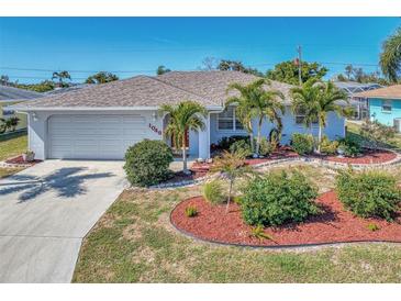 Charming single-story home with well-manicured landscaping, including palm trees and colorful mulch beds at 1048 Ulrey Ln, Englewood, FL 34223