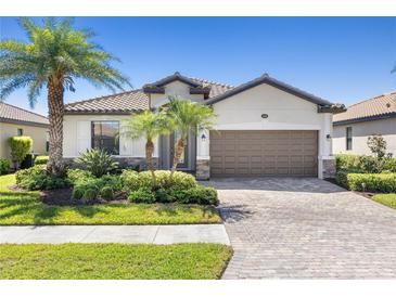 Charming home featuring a tile roof, lush landscaping, and a paved driveway at 12565 Canavese Ln, Venice, FL 34293