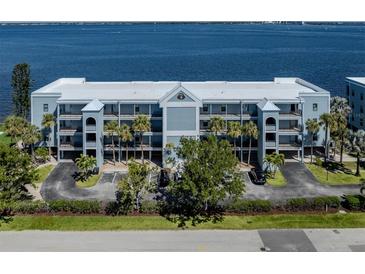 Waterfront condominium building featuring a coastal blue facade, lush landscaping, and balconies with stunning water views at 1750 Jamaica Way # 322, Punta Gorda, FL 33950