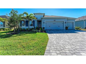 Charming single-story home with well-manicured lawn, lush landscaping, and a gray brick driveway at 1766 Sunset Preserve Way, Port Charlotte, FL 33953
