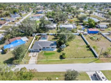 Aerial view of the home with a large yard, bordered with white fence at 2102 Alaric St, Port Charlotte, FL 33952