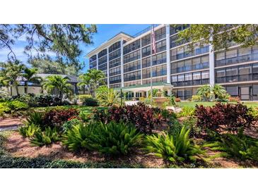 Condo building exterior featuring lush landscaping, water fountain and an American flag waving in the wind at 512 W Venice Ave # 102, Venice, FL 34285