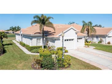 Well-maintained single-story home with a tile roof, lush landscaping, and an attached two-car garage at 651 Back Nine Dr, Venice, FL 34285