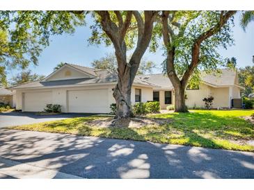 Charming single-story home featuring a neutral color, two-car garage, and mature trees at 109 Southampton N Pl # 245, Venice, FL 34293
