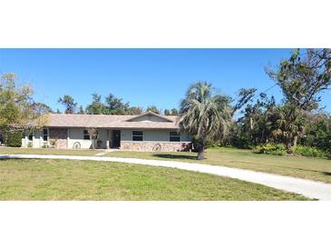 Charming single-story home featuring a well-manicured lawn and decorative rustic accents on the front facade at 1110 Gladstone Blvd, Englewood, FL 34223