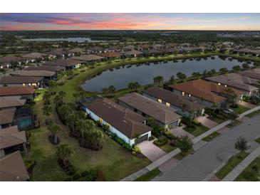 Beautiful aerial view of homes surrounding a lake, with lush landscaping and colorful sunset at 13032 Oriago St, Venice, FL 34293