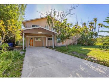 Two story house with a carport, trees, and long concrete driveway at 440 Monza Ave, North Port, FL 34287