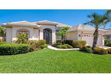 Charming single-story home featuring a well-manicured lawn, lush landscaping, and a welcoming front entrance at 867 Macaw Cir, Venice, FL 34285