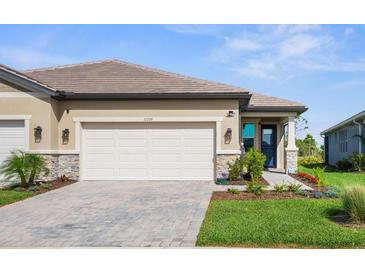 Charming home featuring a well-manicured lawn, paved driveway, and a two-car garage at 11239 Boundless Ter, Venice, FL 34293