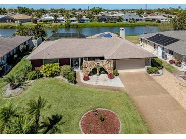 Waterfront home boasts mature landscaping, stone entry arch, and convenient circular driveway at 1229 Waterside Ln, Venice, FL 34285