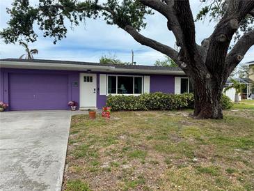 Charming single-story home boasts a bright purple exterior, white trim, and a large tree providing shade at 1460 Everest Rd, Venice, FL 34293