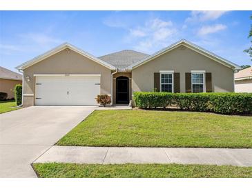 Charming single-story home featuring a well-manicured lawn, two-car garage, and neutral color palette at 25525 Lambert Ln, Punta Gorda, FL 33950