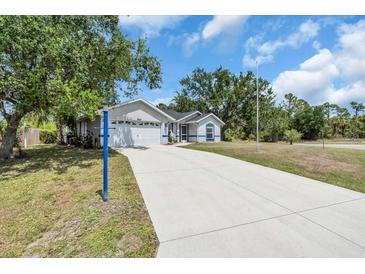 Charming single-story home featuring an attached garage, long drive, and blue trim accents at 2606 Trilby Ave, North Port, FL 34286