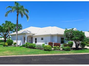 Charming single-story home featuring a white tile roof, lush landscaping, and a vibrant green lawn at 643 Crossfield Cir # 13, Venice, FL 34293