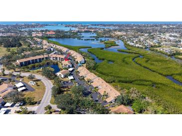 Beautiful aerial view of waterfront condos near lush greenery and a winding coastal inlet at 1130 Bird Bay Way # 184, Venice, FL 34285