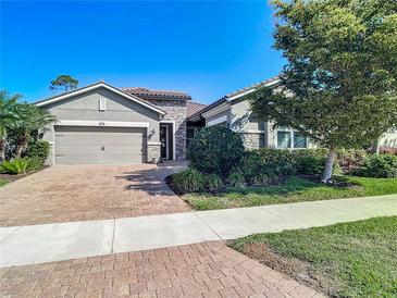 Charming single-story home with a manicured front yard and a two-car garage, showcasing stone accents and brick pavers at 11700 Tapestry Ln, Venice, FL 34293