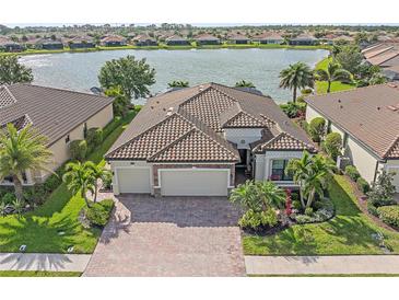 Stunning lakefront home with a tile roof, paver driveway, and lush landscaping at 13215 Amerigo Ln, Venice, FL 34293