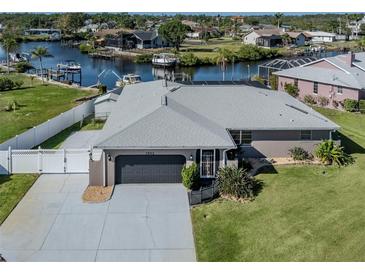 Waterfront home featuring a two-car garage and a well-manicured lawn with direct access to the canal at 1503 Marlin St, Nokomis, FL 34275