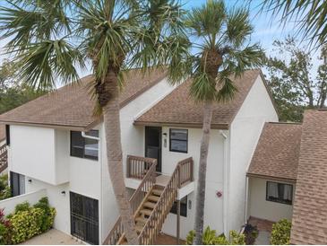 Charming two-story condo with palm trees and a wooden staircase leading to the front door at 758 Bird Bay W Dr # 169, Venice, FL 34285