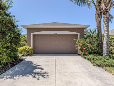 Attached garage with driveway, and landscaping on a sunny day at 11924 Tempest Harbor Loop, Venice, FL 34292