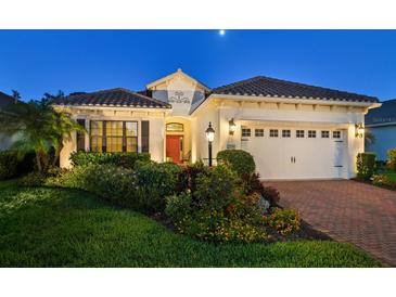 Charming single-story home featuring a red tile roof, lush landscaping, and a brick paver driveway at 27336 Driver Ln, Englewood, FL 34223