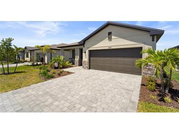 Inviting single-story home featuring a paver driveway, a two-car garage, and well-manicured landscaping at 1608 Saddlewood Cir, Port Charlotte, FL 33953