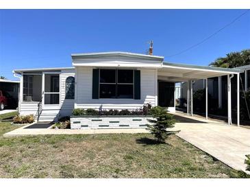 Charming single-story home featuring a carport, screened porch, and beautifully landscaped front yard at 235 Trailorama Dr, North Port, FL 34287